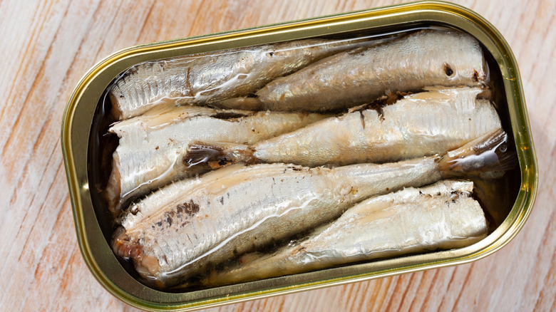 Canned sardines in oil on a wooden surface