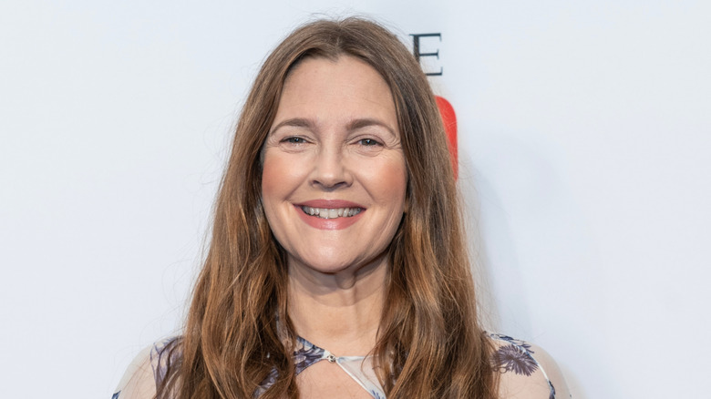 Drew Barrymore smiling in a blue and white patterned dress