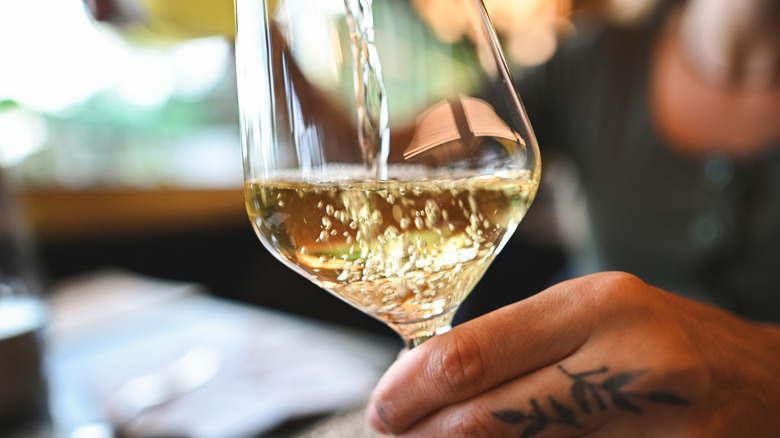 A person pouring a glass of white wine.