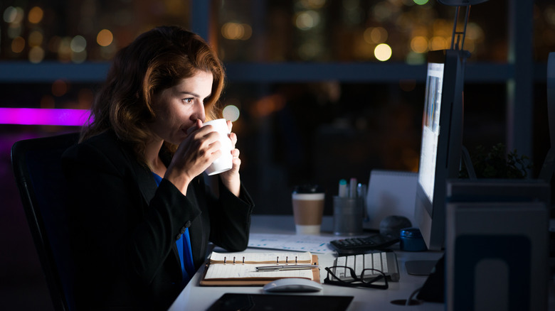 Business woman drinking coffee to get some energy for working overtime.