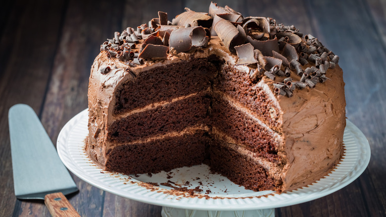 A cut chocolate layer cake on a cake stand