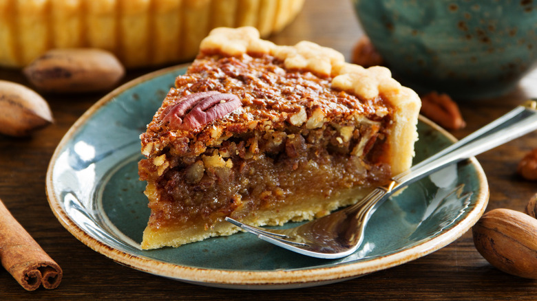 A slice of pecan pie on a plate with a fork