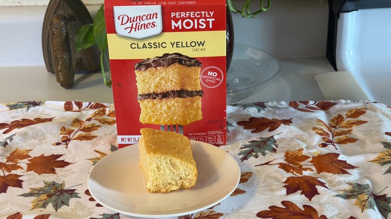 A piece of Duncan Hines plain yellow cake on a plate in front of the box.