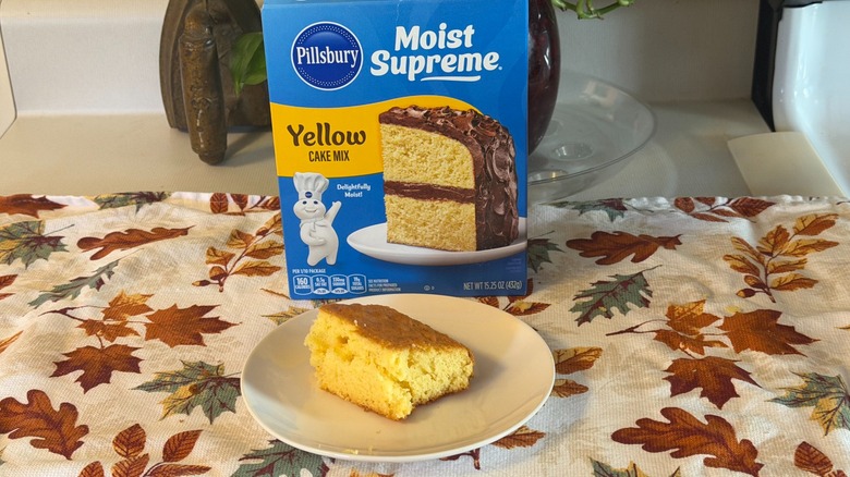 A piece of plain Pillsbury yellow cake on a plate in front of the box.