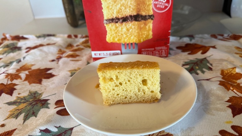 A piece of Duncan Hines yellow cake with no frosting on a plate in front of the box.