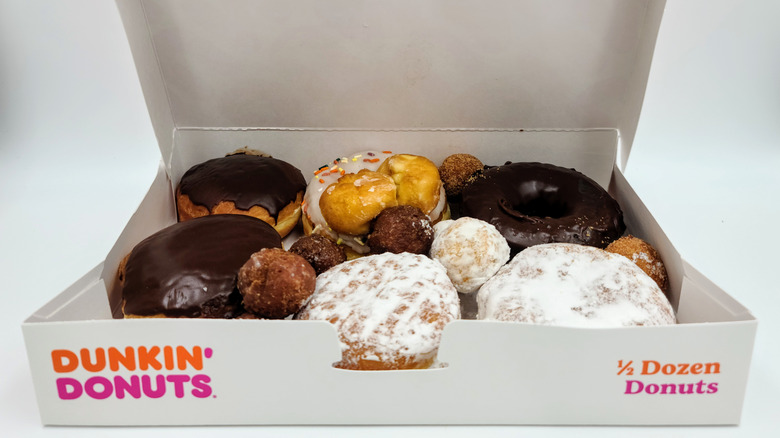 Mixed flavour donuts in cardboard box, takeout food from Dunkin' Donuts, chocolate and frosted