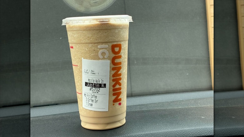 A close up of a Dunkin' frozen coffee order against a grey background