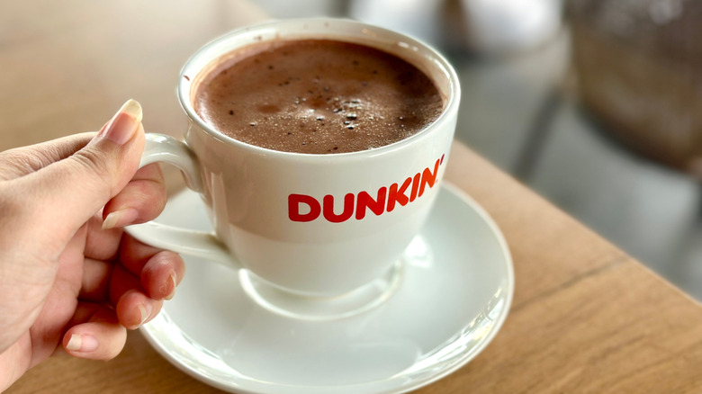 Hand's holding a cup of Dunkin' famous hot chocolate