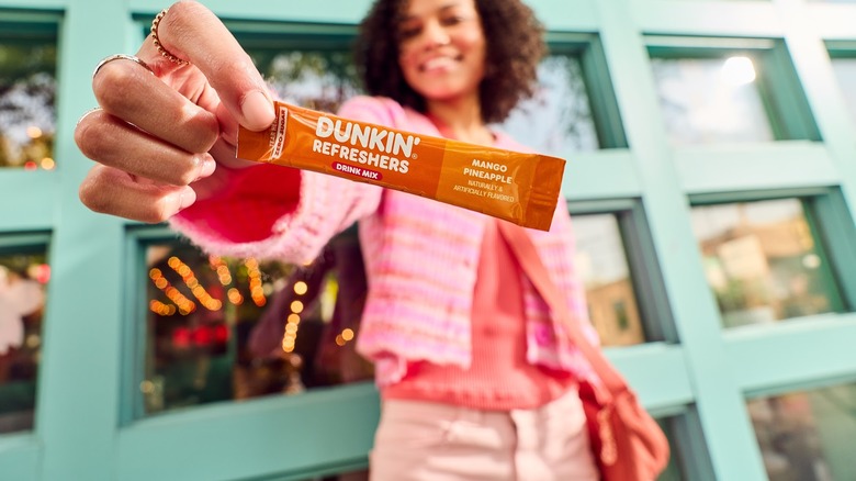 Woman holding out Dunkin' Refresher Drink Mix stick