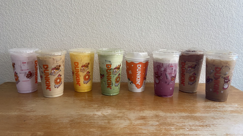 All eight drinks in a horizontal row on a wooden table.