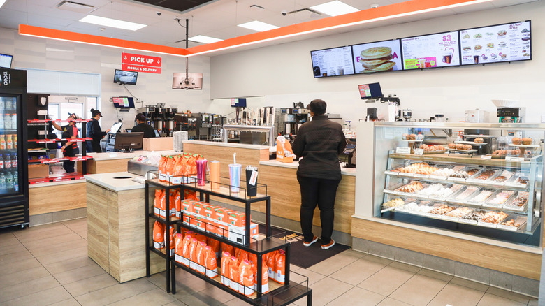 The inside of a dunkin' location with customer at register
