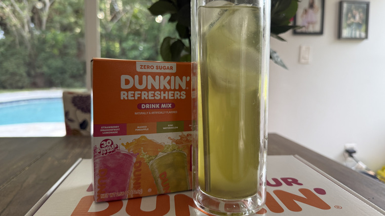 Dunkin' Kiwi Watermelon Refresher in glass with ice on top of box