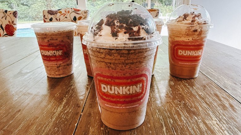 Dunkin's Oreo Caramel Creme Coffee Chiller with other drinks in background on a wooden table