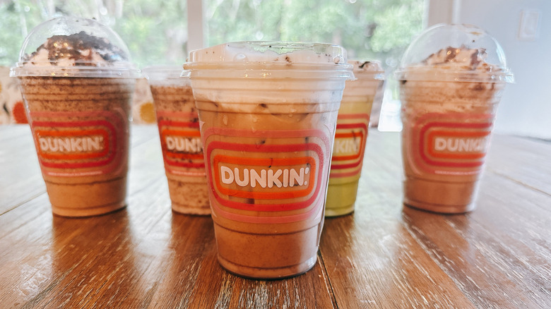 Dunkin Donuts Oreo Cloud Latte with other drinks in background on a wooden table