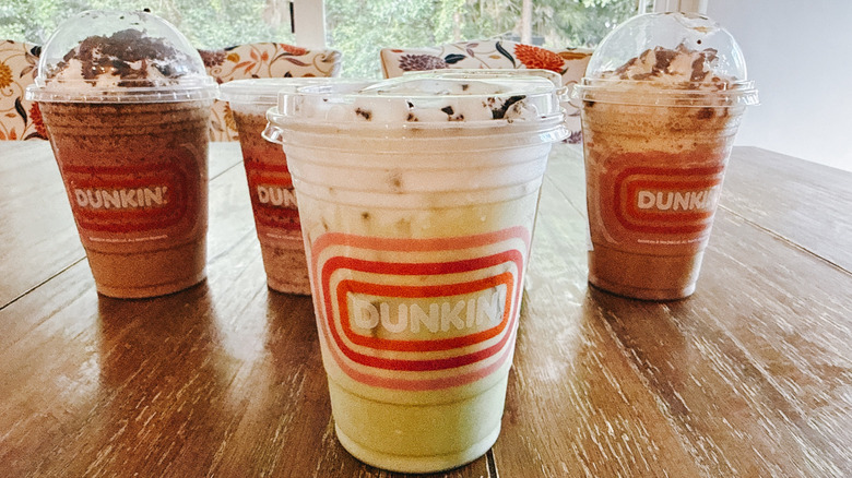 Dunkin's Oreo Matcha Latte with other drinks in background on a wooden table