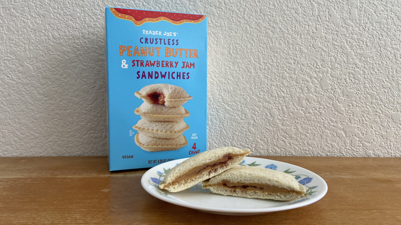 a halved Crustless Sandwich on a plate with its box in the background