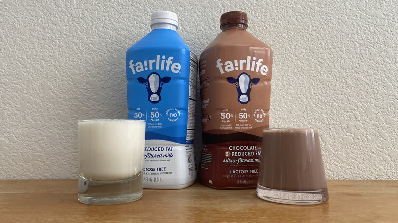Bottles of Fairlife ultra-filtered milk and chocolate milk centered with full glasses on either end