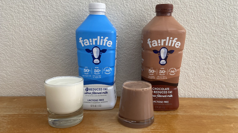 Fairlife ultra-filtered milk and chocolate milk beside a full glass of each poured out
