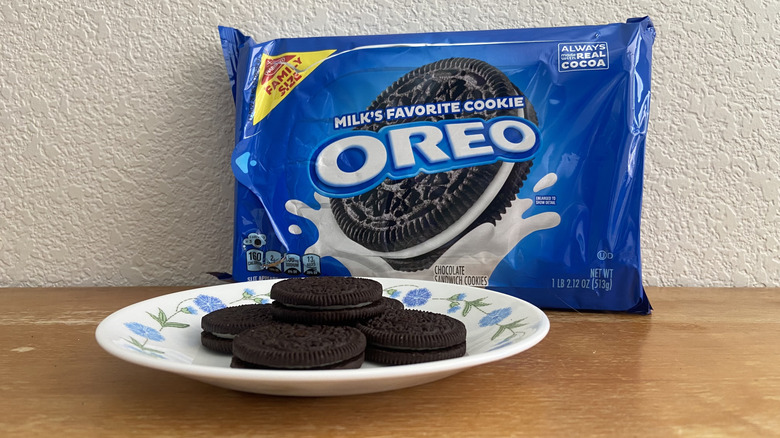 a pile of Oreos on a small plate in front of their packaging