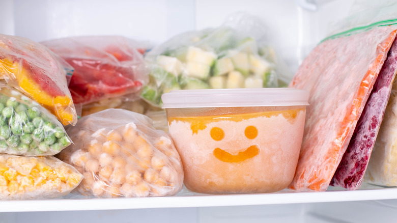 A freezer stocked with frozen ingredients, with a smiley face traced in the ice on a container