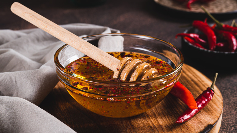 Glass bowl of hot honey with fresh and dried chiles