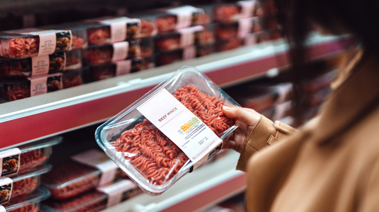 Someone looking at a package of ground beef in the grocery store