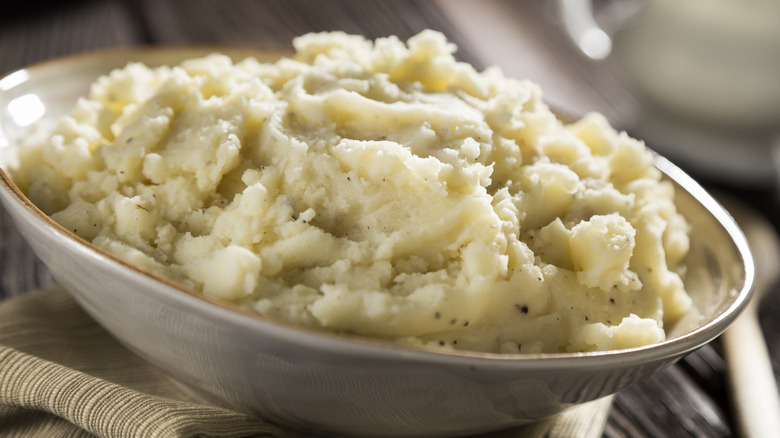 Chunky mashed potatoes seasoned with black pepper in a white bowl