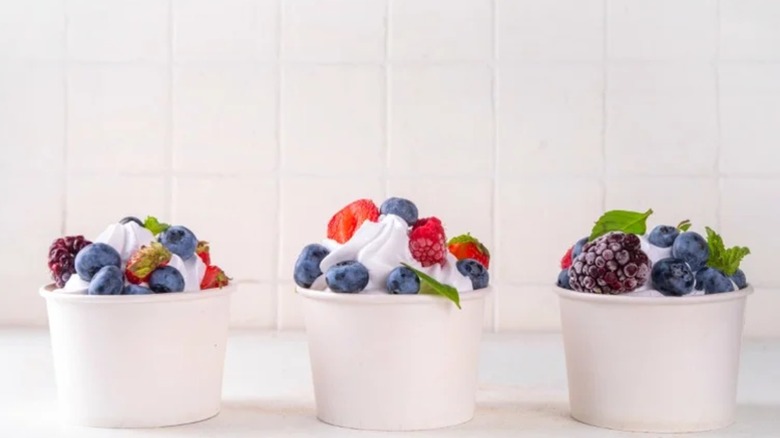 Three cups of homemade frozen yogurt topped with berries and mint