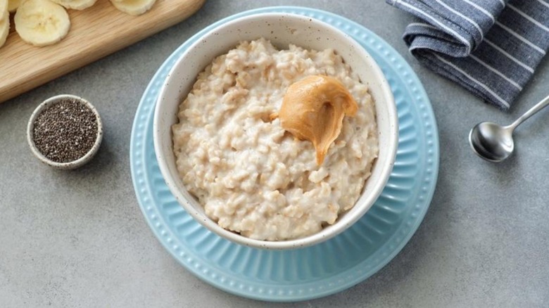 A white bowl of protein oatmeal topped with peanut butter and served with chia seeds