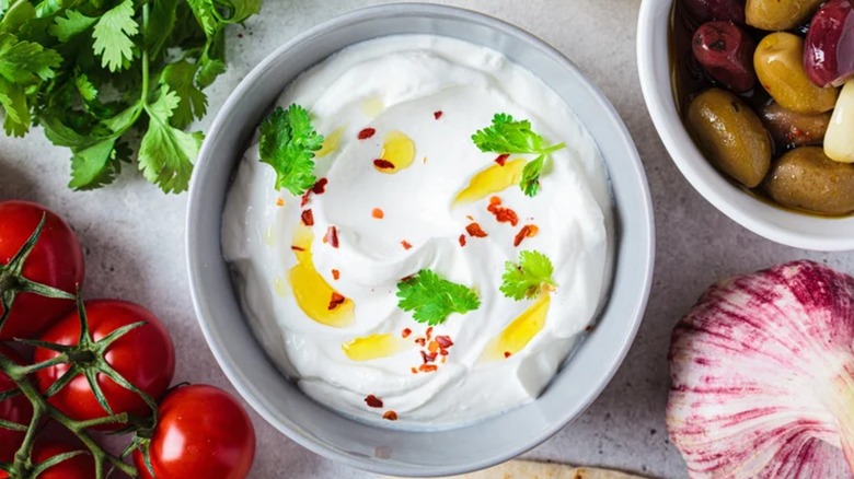 A white bowl of whipped feta cheese made with Greek yogurt, olive oil, and herbs
