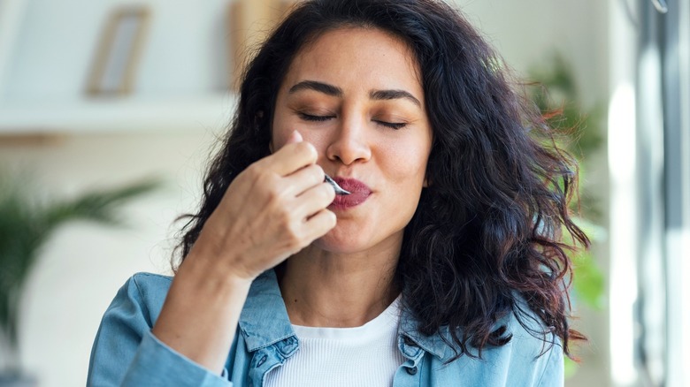 Person eating from spoon and smiling