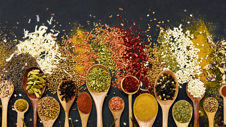A mix of dried herbs and spices in wooden spoons