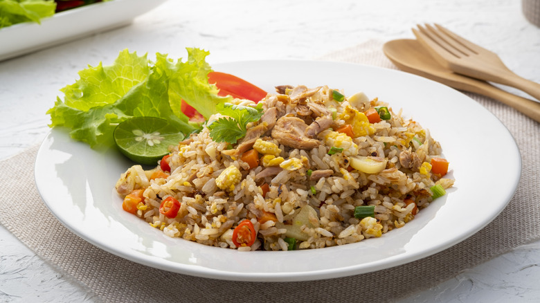 Stir fry rice with chili peppers, veggies, and bits of scrambled egg and meat on plate