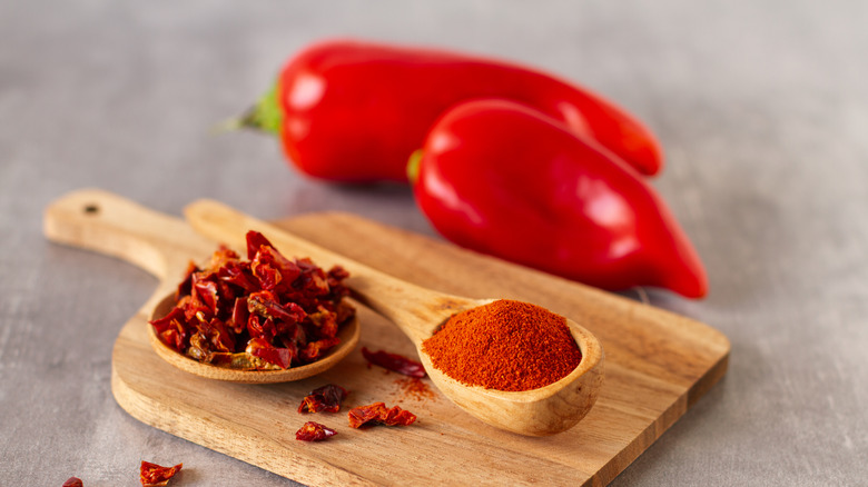 Dried chili peppers and powder on a wooden cutting board