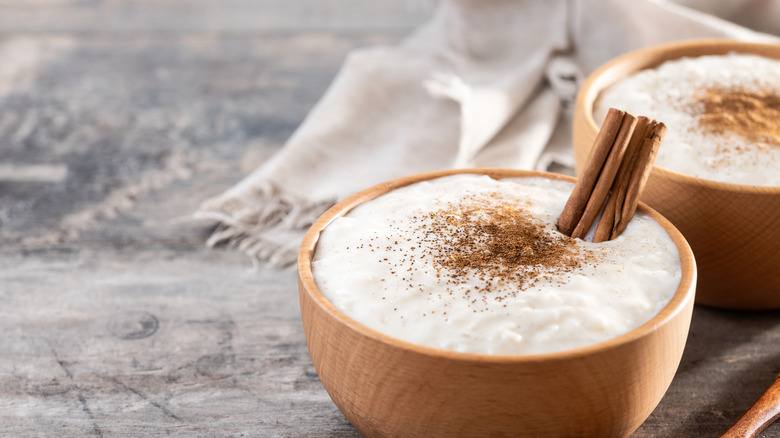 Rice pudding in a wood bowl with cinnamon sticks and sprinkled with cinnamon