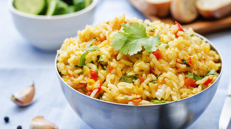 A bowl of cooked rice with chopped vegetables and fresh parsley