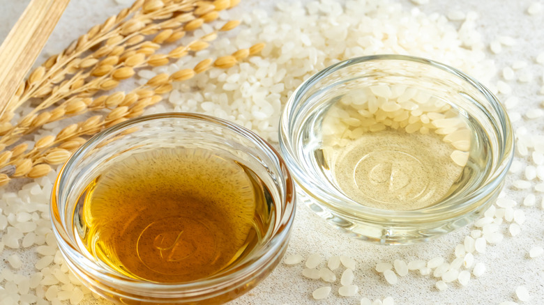 Small bowls of vinegar amid uncooked white rice grains
