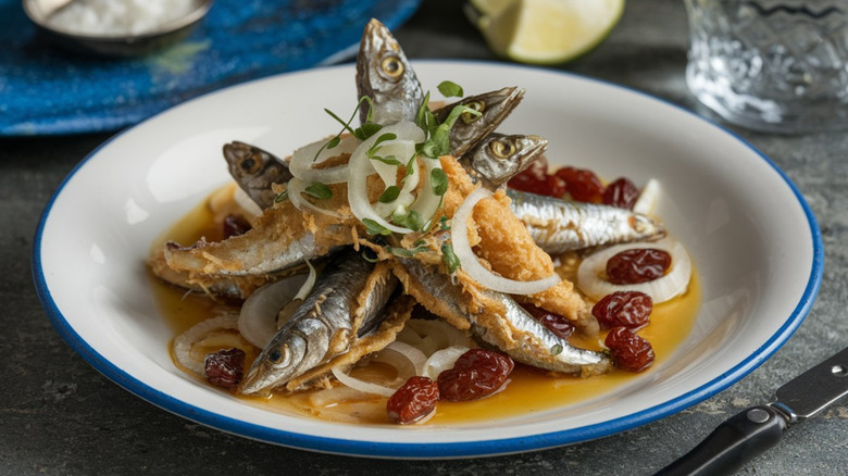 Fried sardines with onions and raisins on plate