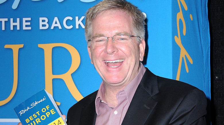 Rick Steves laughing, holding book