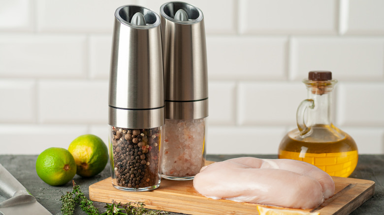 Electric spice grinders on a table with raw chicken and other vegetables