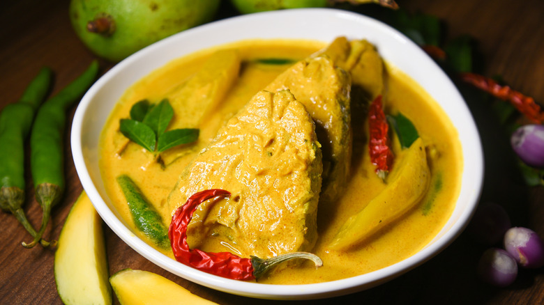 A bowl of kerala meen moilee with fish, coconut milk, and green mango