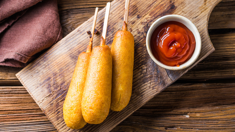 A stack of three corn dogs served with ketchup for dipping