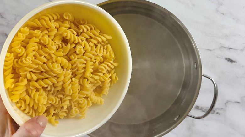 Fusilli pasta going into pot of water