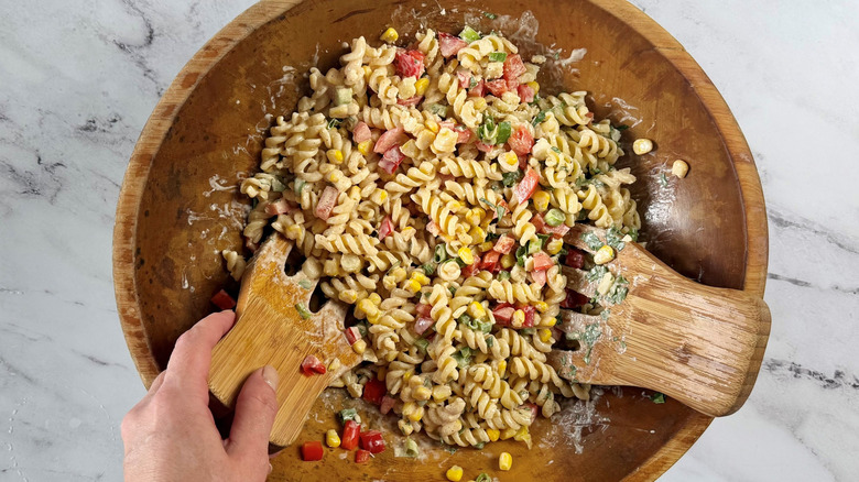 Pasta salad with wooden salad mixers in bowl