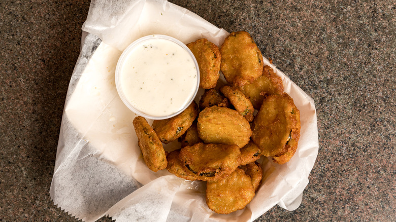 A basket of deep-fried pickles served with ranch dressing