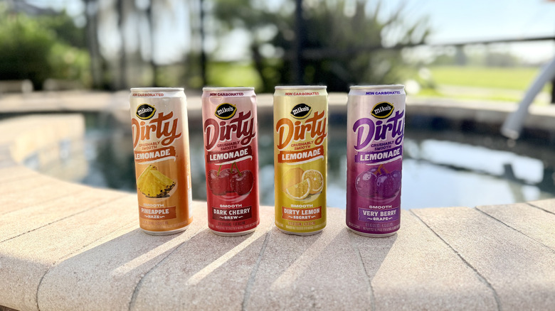 Four colorful cans of Mike's Dirty Lemonade on the side of a pool