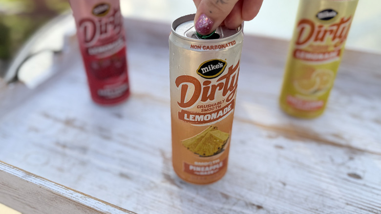 Person's hand opening a can of Mike's Hard Dirty Lemonade in Pineapple Haze flavor