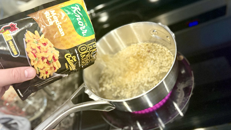 Hand pouring a packet of Knorr rice into a pan