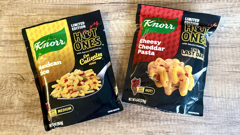 Two packets of Knorr Hot Ones Mexican rice and cheesy pasta on a wooden background