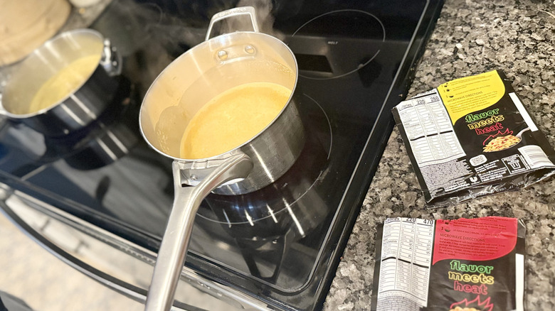 A stove top with two pans on it next to two empty packets